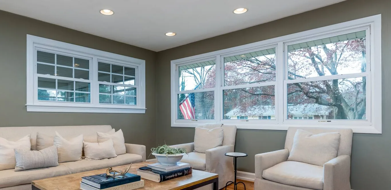 A living room with a long run of wide white windows across two walls