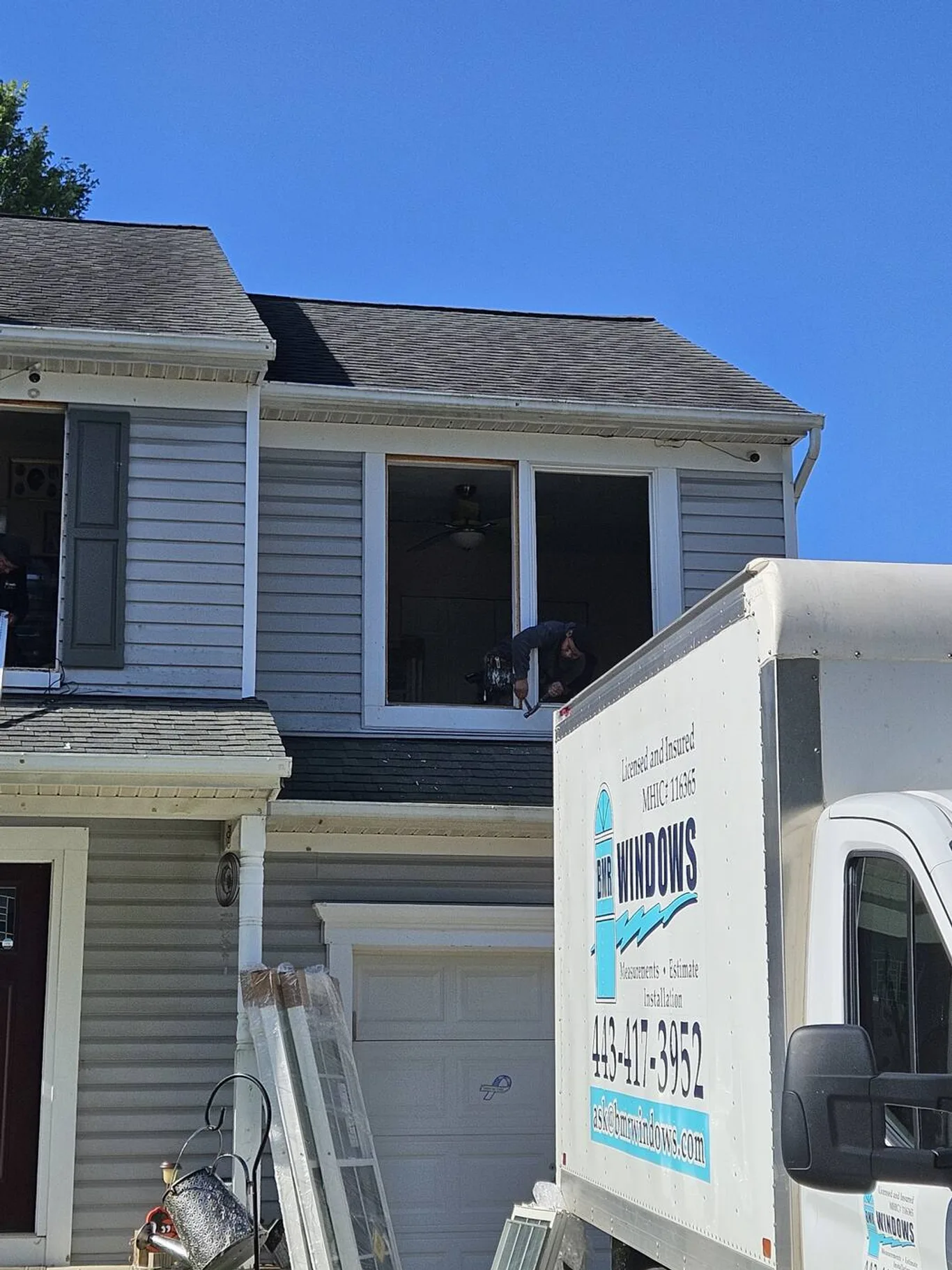 BMR's truck beside a house, lettered with the phone number and MHIC 116365, an installer at an upstairs window