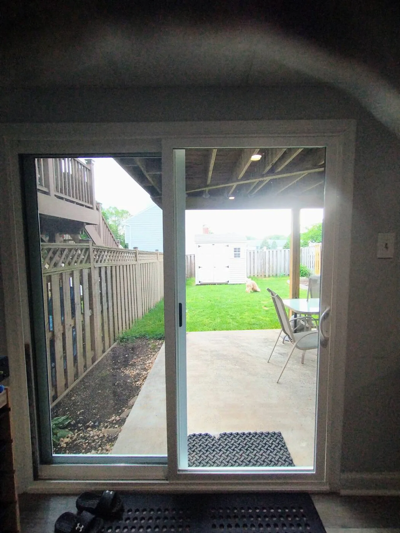 A sliding door seen from inside, open to a patio and fenced yard