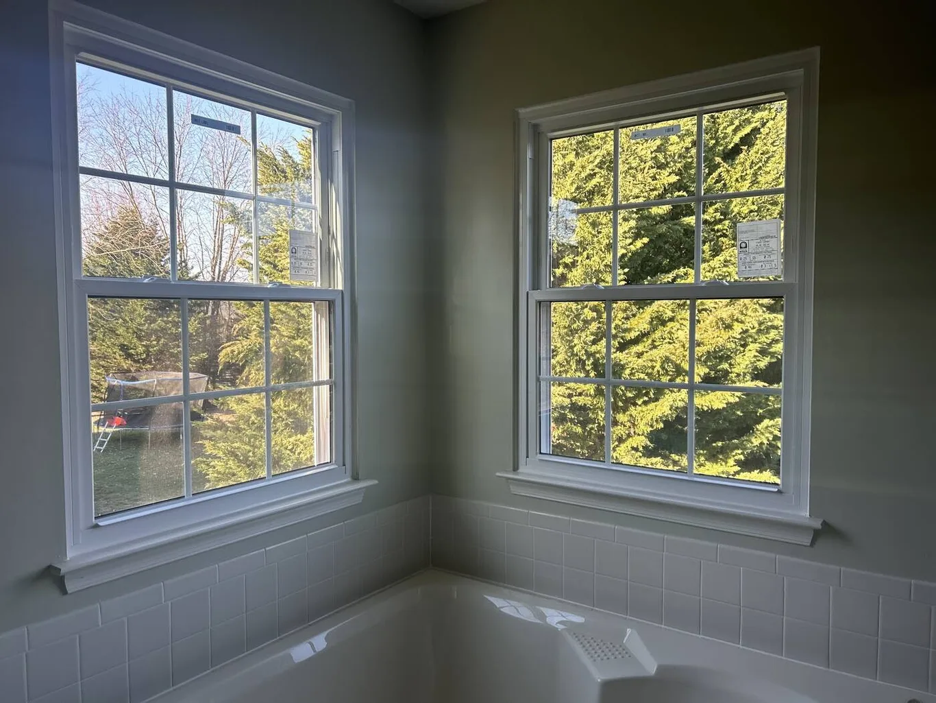 Two new windows meeting at a corner above a bathtub