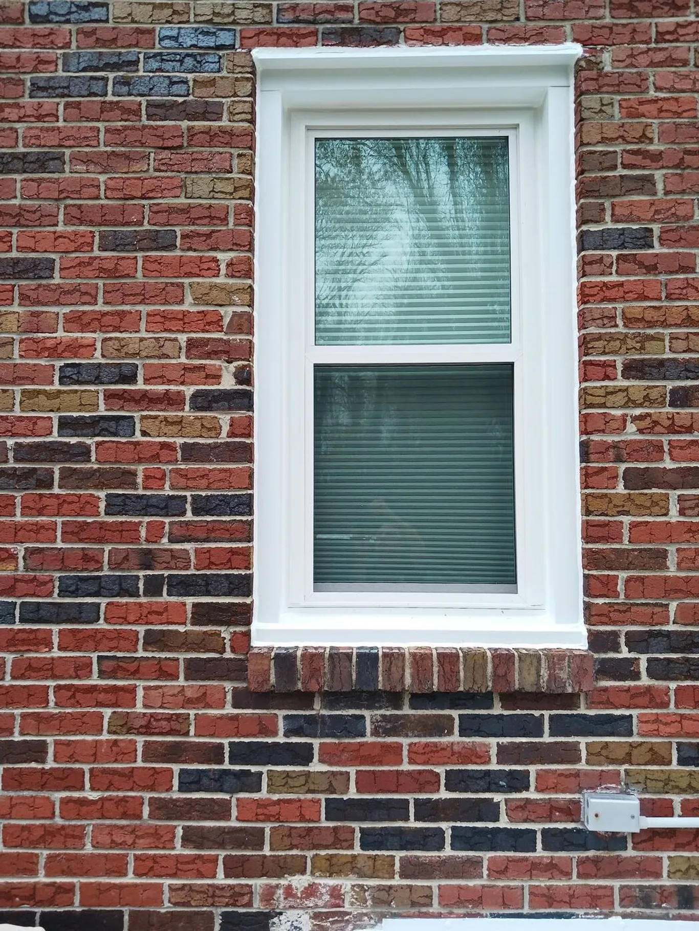 A single new white window set into a red brick wall