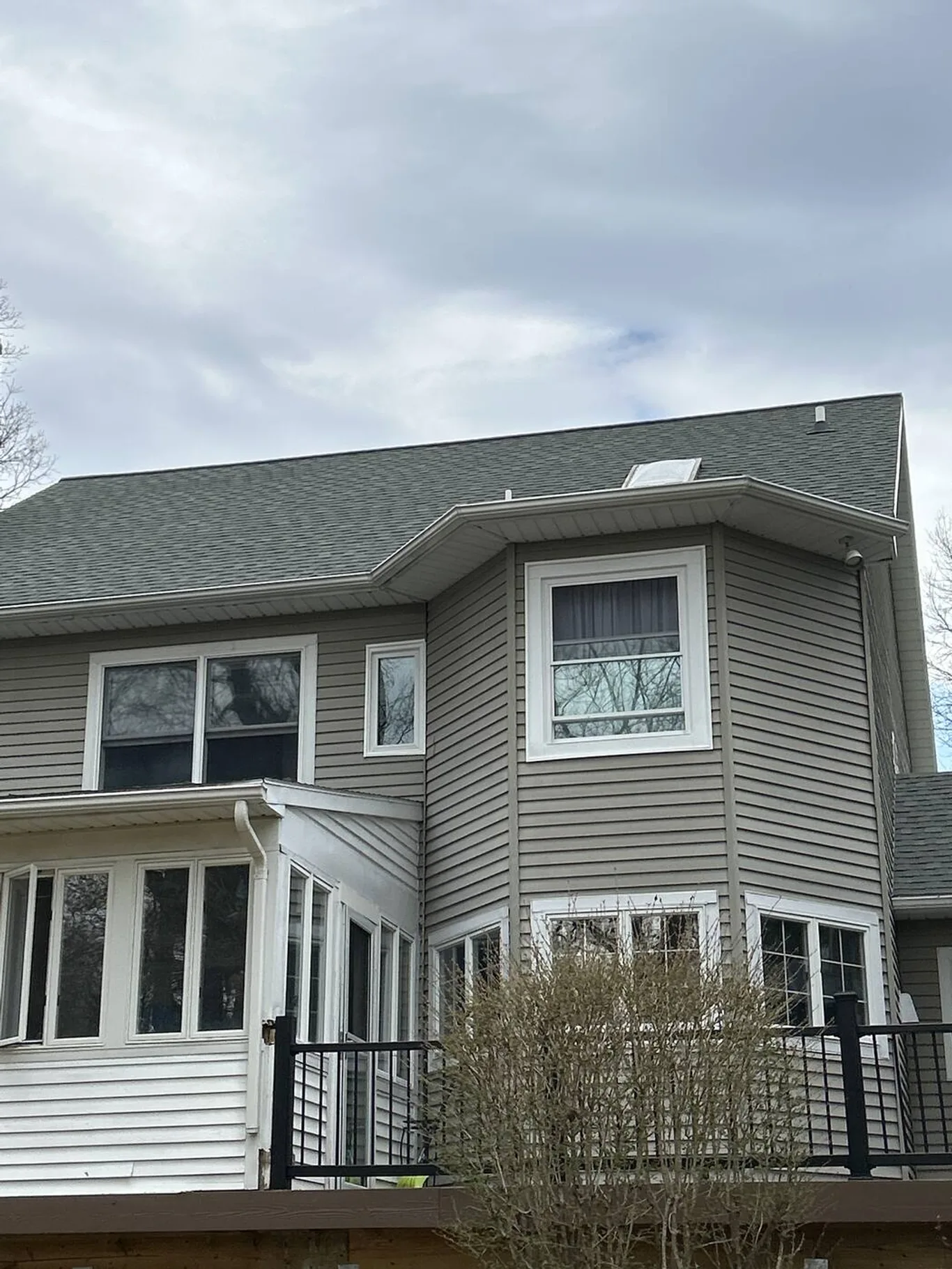 The back of a grey-sided house with several new windows on both floors