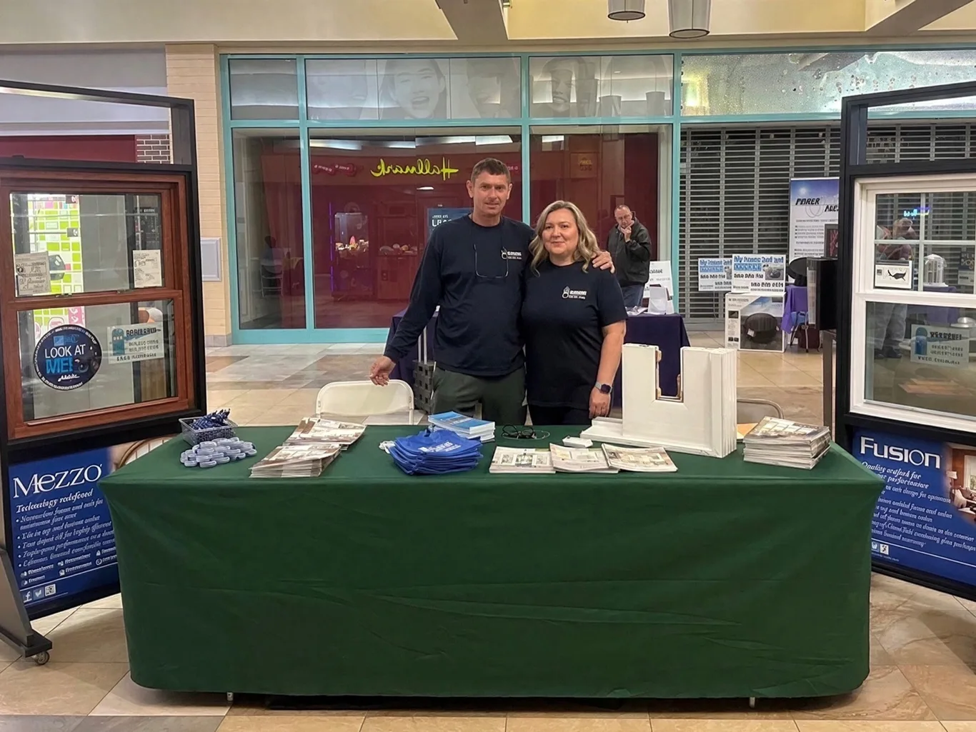 Mike and Marta of BMR Windows in BMR shirts behind a display table, with window samples on either side.