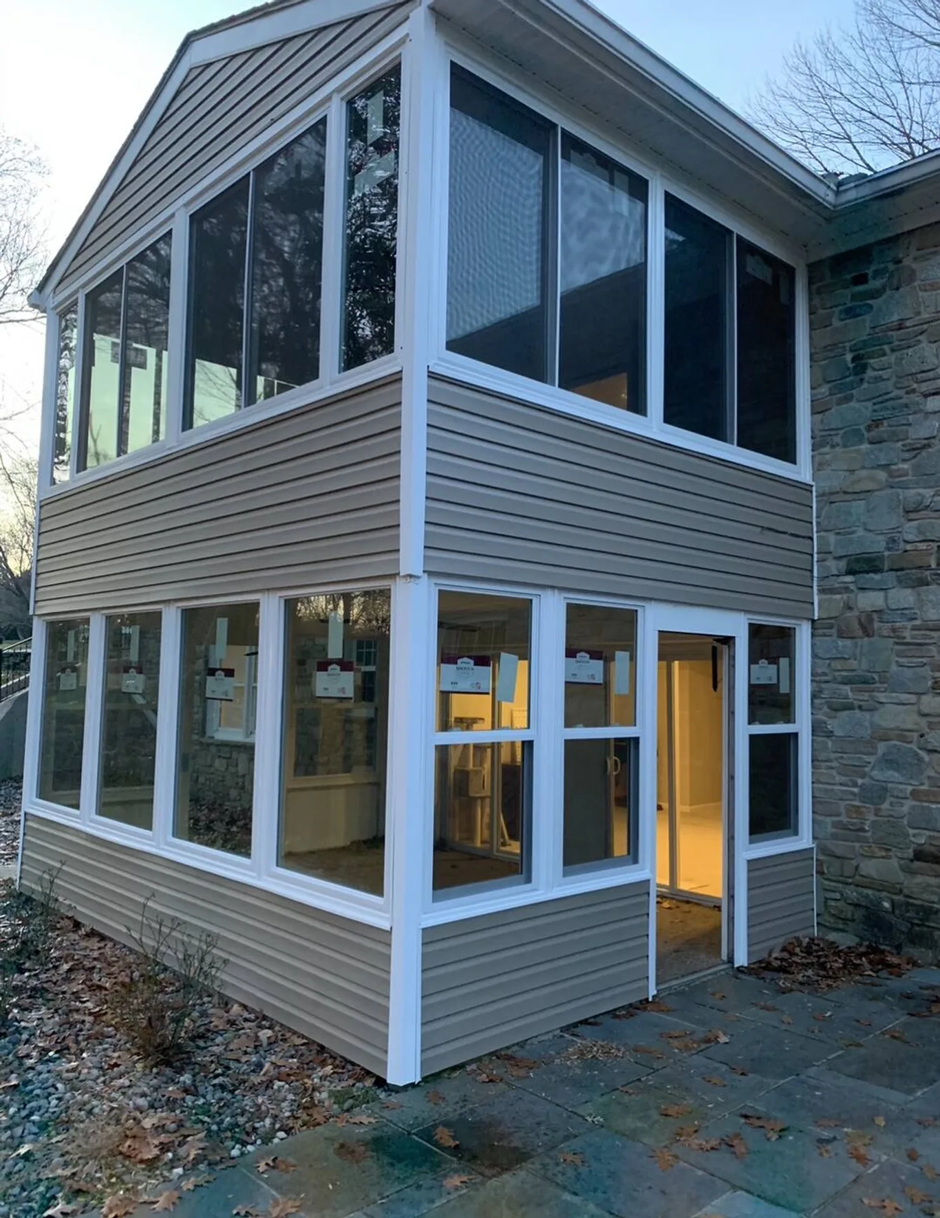 A two-storey addition clad in siding with windows wrapping both floors and a glass door