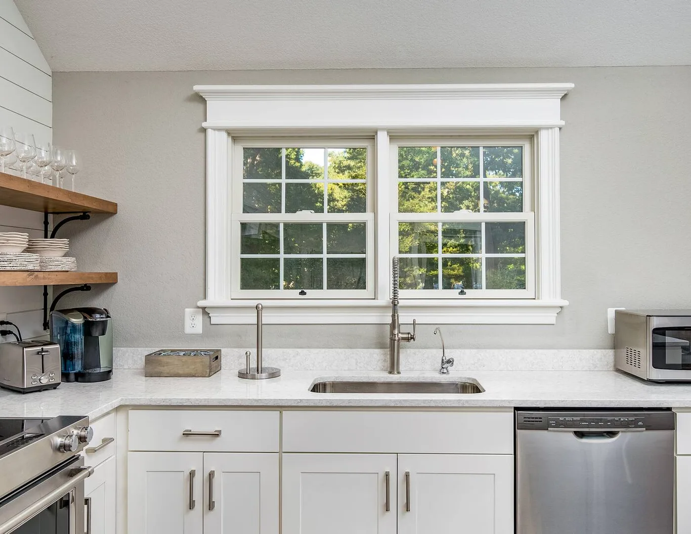 A double window with grilles above a kitchen sink, wide white trim around it