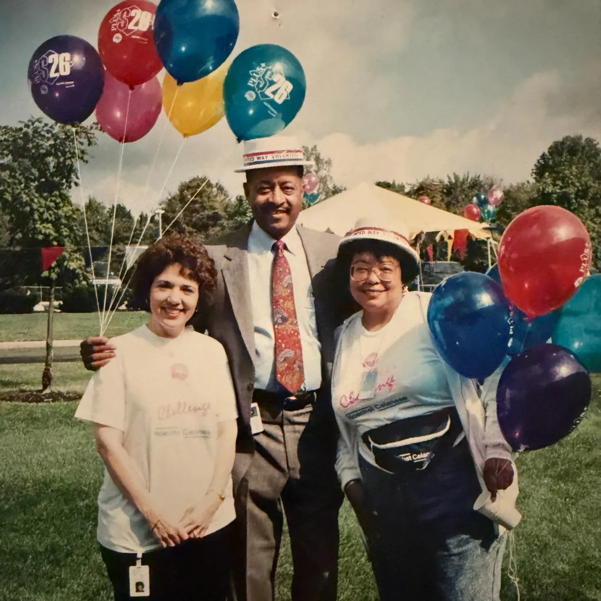 Barbara outdoors with two friends, holding a bunch of balloons