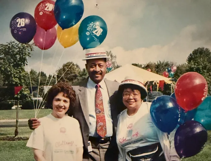 Barbara outdoors with two friends, holding a bunch of balloons